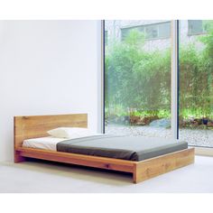 a bed sitting next to a window in a room with white walls and flooring