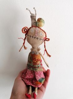 a hand holding a small doll in it's right hand