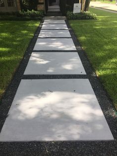 a walkway in front of a house with grass and trees