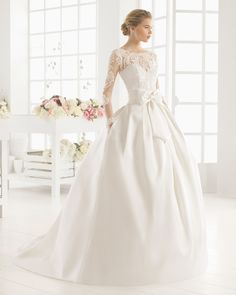 a woman in a white wedding dress standing next to a table with flowers on it