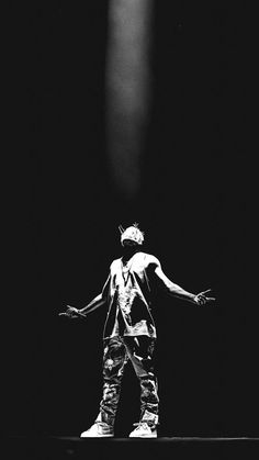 a black and white photo of a person standing on stage with his arms spread out