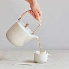 a person pouring tea into a white cup