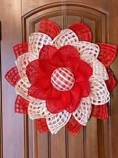 a red and white wreath hanging on the front door with burlocked mesh