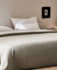 a bed with white sheets and pillows in a room