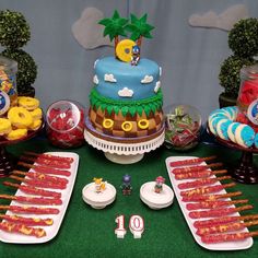 a table topped with lots of desserts and cake covered in fondant on top of green grass