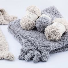 three balls of yarn are laying on top of each other, one is gray and the other is white