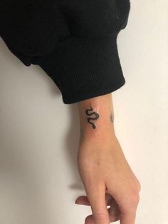 a person's hand with a small tattoo on the left wrist and an omen symbol on the right wrist