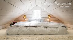 an attic bedroom with white painted walls and wood paneled ceiling, made up to be used as a bed