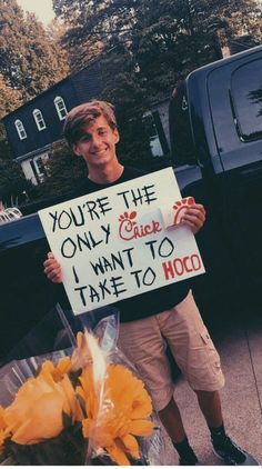 a man holding a sign that says you're the only one i want to take to hoco