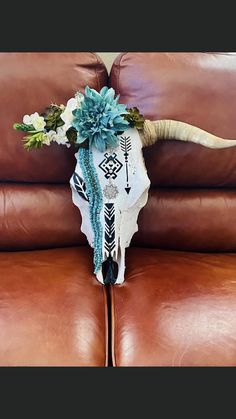 a cow skull with flowers on it sitting on a leather couch