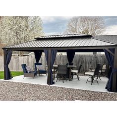 a patio covered in blue curtains next to a wooden fence and table with chairs on it