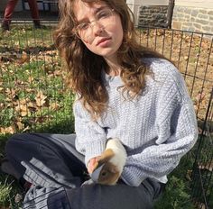 a woman sitting on the ground holding a roll of toilet paper in her hand and looking at the camera