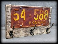 an old kansas license plate mounted to a wall with hooks on the front and back