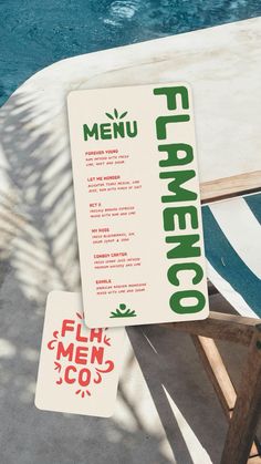 a menu sitting on top of a wooden table next to a swimming pool