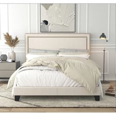 a white bed sitting in a bedroom on top of a wooden floor next to a lamp