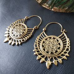 Openwork Hoop Earrings in Silver or Gold Brass. These Creoles are Elegantly Decorated with the Flower of Life Pattern Surrounded By A Circle. The Circle Of The Hoops Is Decorated With Spikes To Give These Earrings A More Ethnic Style. The Powerful Flower of Life Symbol Of Sacred Geometry Releases Good Waves. The Flower of Life Symbolizes Regeneration, Creation and Metamorphosis. She Represents the Cycle of Life. These Hoop Earrings are very elegant and they will illuminate your face. Timeless and Lightweight Creoles to Wear Everyday to Give an Ethnic Touch to Your Outfits. They are made from brass. Material: Brass Color: Silver or Gold Length: 5.7cm Width: 3.5cm Thickness: 0.2 cm Weight: 14 Gm The Pair Handmade Delivered in a Fabric Pouch Ideal for Gifting To offer or simply treat yourself Festival Dangle Hoop Earrings With Latkans, Metal Hoop Earrings For Festivals, Bohemian Dangle Hoop Earrings With Latkans, Bohemian Teardrop Hoop Earrings With Ear Wire, Bohemian Teardrop Nickel Free Hoop Earrings, Festival Dangle Metal Hoop Earrings, Bohemian Teardrop Single Plug Earring, Festive Dangle Metal Hoop Earrings, Festival Metal Dangle Hoop Earrings