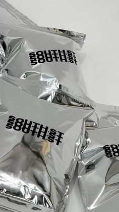 some silver foil bags with black letters on them