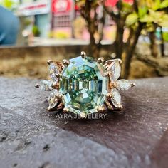 an aqua green ring sitting on top of a wooden table in front of a tree