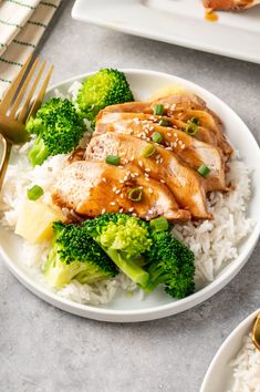 a white plate topped with chicken and broccoli covered in sesame seeds on top of rice