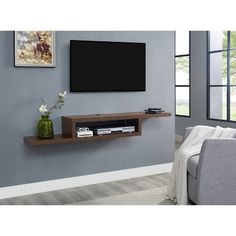 a flat screen tv mounted to the side of a wall next to a gray couch