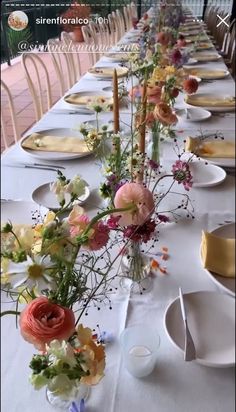 a long table with plates and flowers on it