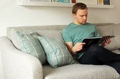 a man sitting on a couch reading a book