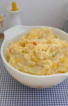 a white bowl filled with mashed potatoes on top of a blue checkered table cloth