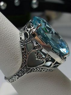 24ct. Simulated Aquamarine Sterling Silver RingOval Beast Design#D76 This is a new beautiful Victorian reproduction ring cast in solid sterling silver. The gorgeous filigree ring is set with a huge approximately 24 carat simulated blue aquamarine gemstone. The stunning gem is 17mm (11/16") wide x 23mm(15/16") long. The ring is 12mm off the finger. The inside of the band is marked 925 for sterling silver. Notice the craftmanship of the sterling silver setting. The large stone is accented by the b Exquisite Oval Filigree Ring, Exquisite Oval Filigree Promise Ring, Oval Filigree Ring With Intricate Design For Collectors, Art Deco Oval Filigree Engraved Ring, Art Deco Engraved Oval Filigree Ring, Silver Topaz Ring In Art Deco Style For Gifts, Art Deco Silver Topaz Ring For Gift, Exquisite Silver Oval Topaz Ring, Exquisite Silver Oval Filigree Ring