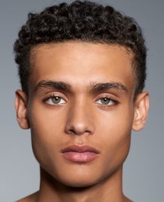 a young man with curly hair is looking at the camera and has his eyes open