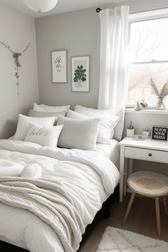 a white bed sitting under a window next to a table with a lamp on it