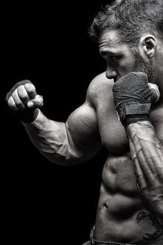 a shirtless man with his arm wrapped around the wrist and holding a pair of boxing gloves