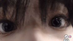 a close up of a person's eyes with black hair