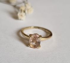 a close up of a ring on a white surface with flowers in the back ground