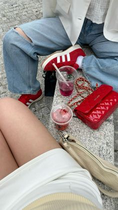 a woman sitting on the ground with her legs crossed and purse next to her feet