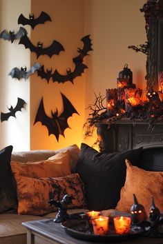 a living room decorated for halloween with candles and bats hanging from the fireplace mantel