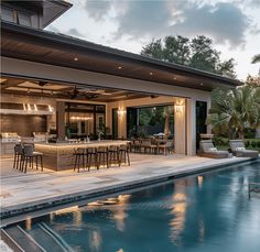 an outdoor kitchen next to a pool with chairs and bar stools on the patio