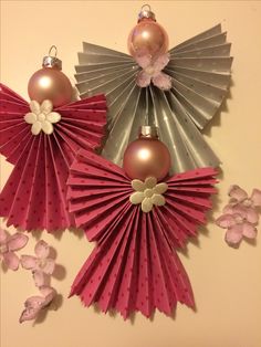 three paper fan ornaments are hanging on the wall next to pink and silver decorations with white polka dots