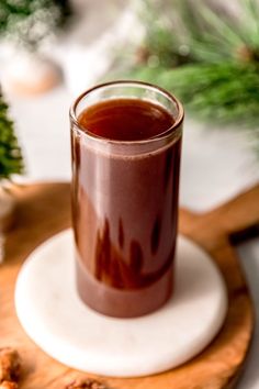 a glass filled with liquid sitting on top of a wooden tray next to pine cones