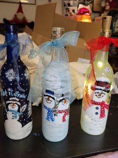 three wine bottles with snowmen on them are sitting next to each other, wrapped in plastic