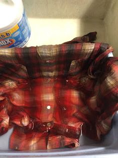 a red and black flannel shirt sitting on top of a sink next to a bottle of toothpaste