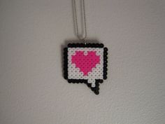 a necklace with a pink heart in the shape of a speech bubble hanging from a chain