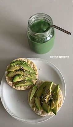 an avocado sandwich on a plate next to a jar of green smoothie