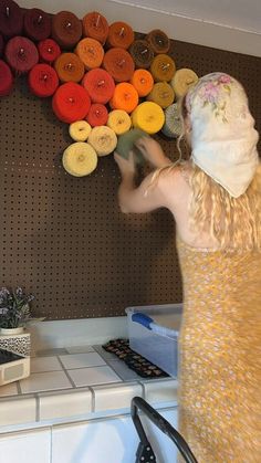 a woman standing in front of a wall with yarn on it