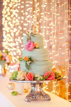 a three tiered cake with flowers on the top is sitting on a silver platter