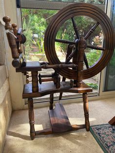 a spinning wheel sitting on top of a wooden stand next to a glass window in a room