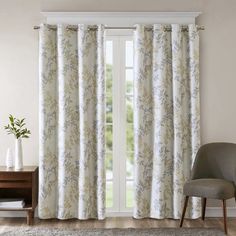 a living room with a chair and window covered in white drapes next to a rug