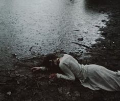 a woman is laying on the ground in the rain