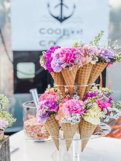 three cones filled with flowers sitting on top of a white table covered in confetti