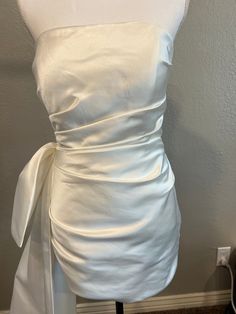 the back of a white dress with a bow at the waist and shoulder, on a mannequin dummy