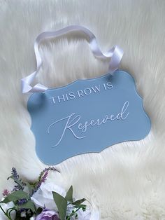 a blue sign that says this row is reserved next to some purple and white flowers